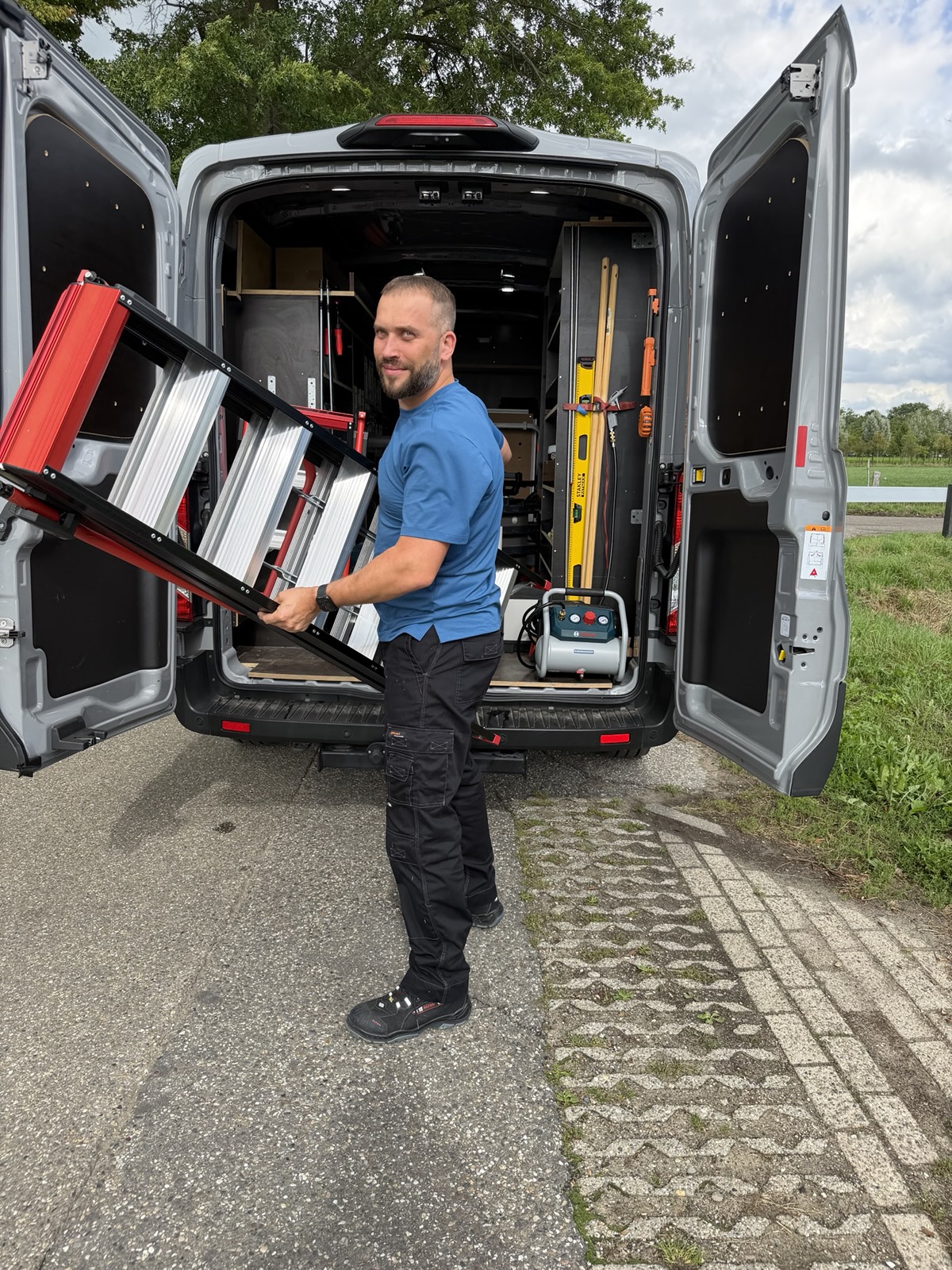 Rinze de Dreu bij zijn bedrijfsbus, met een ladder in de hand